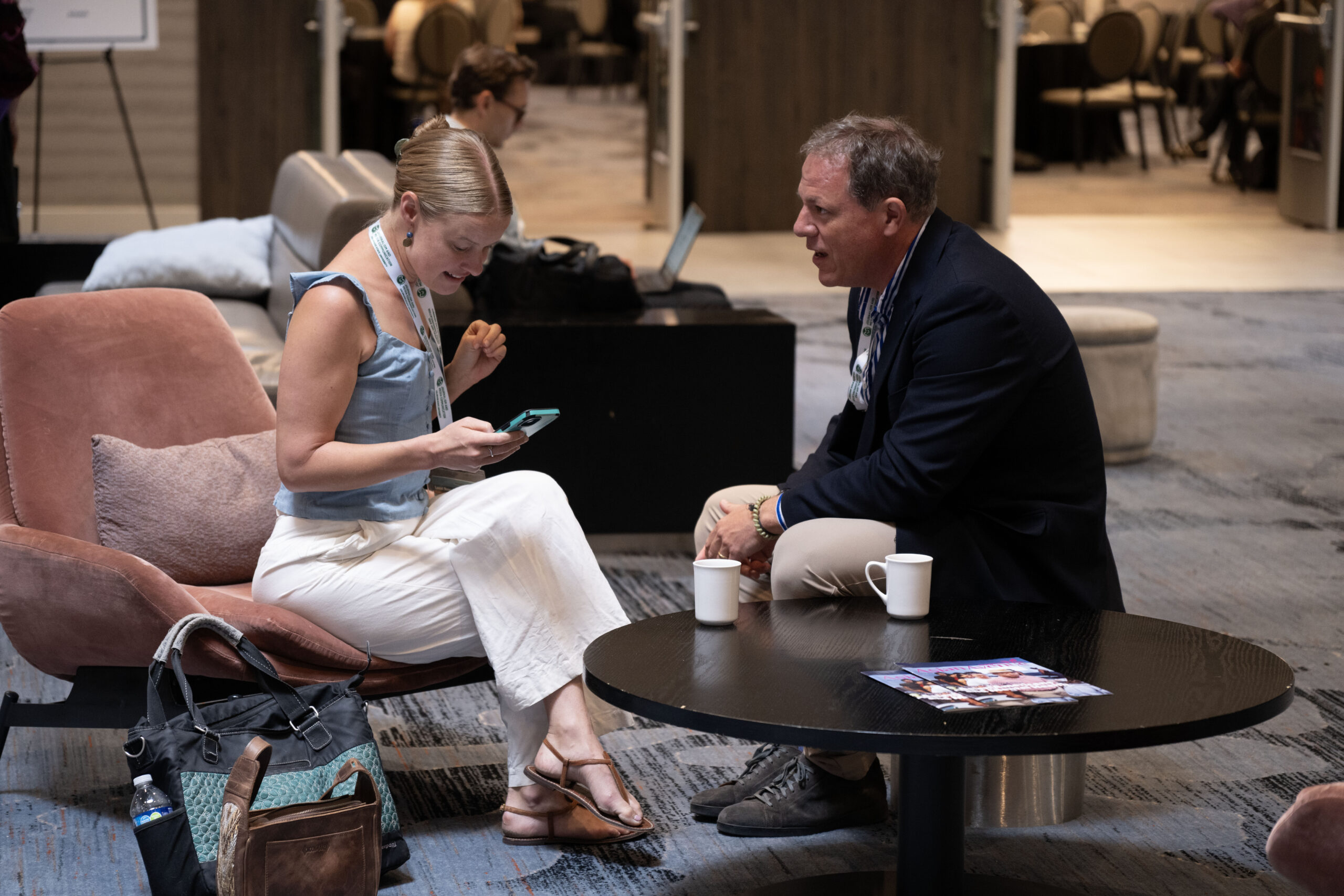 Two attendees talking over coffee in a lounge at Local News Solutions.