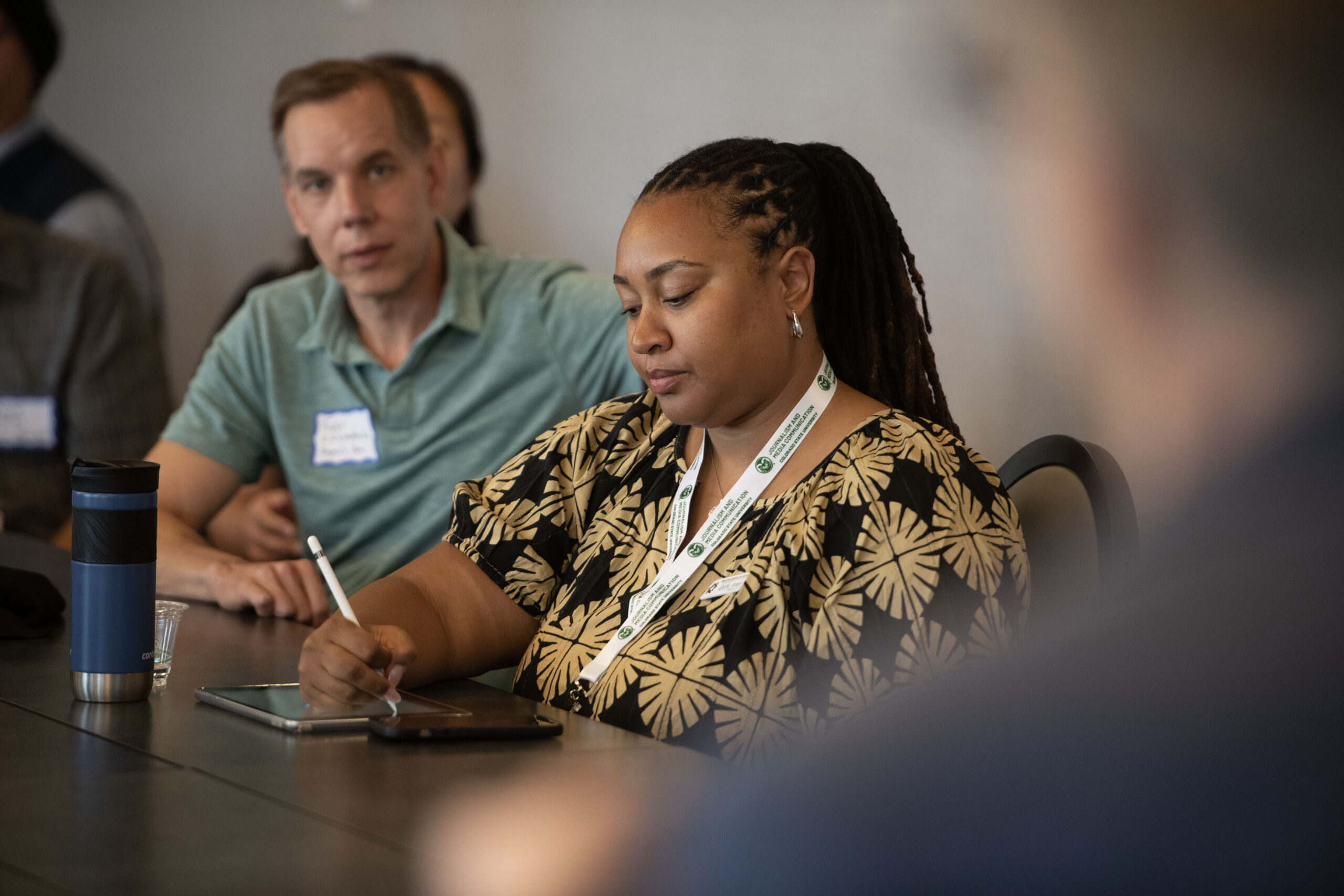 An attendee taking notes while seated at a conference table.