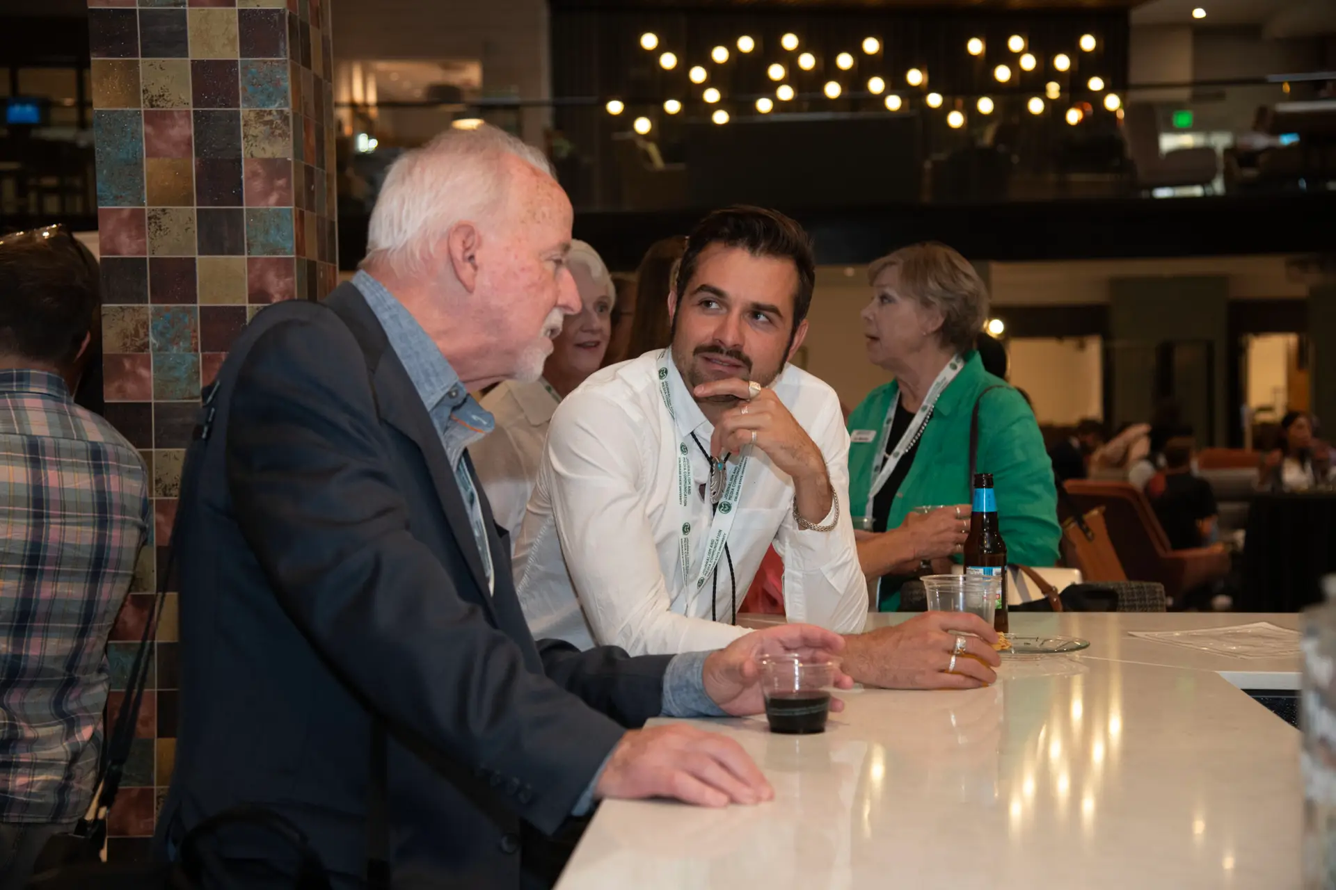 Two attendees talking during an evening reception at Local News Solutions.