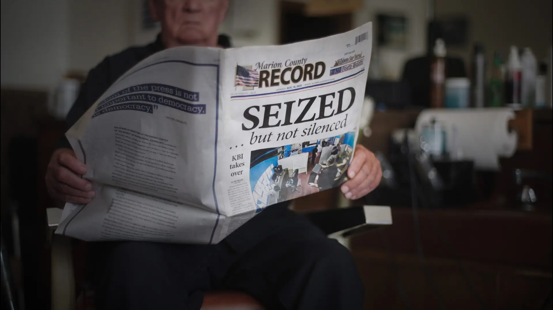 A person holds an open Marion County Record newspaper with the headline “SEIZED … but not silenced.”
